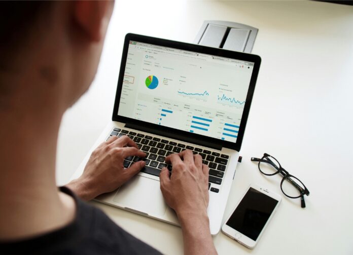 a person writing in front of a laptop and he is working for an index prices