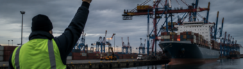 Port worker raises a fist at a container terminal during a 24-hour warning strike affecting six German seaports.