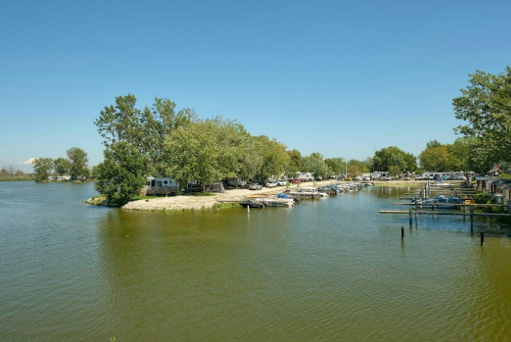 Boats docked at a sunny lakeside campground with trees