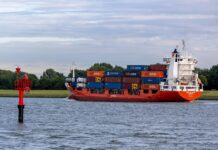 Shipowners expand orderbooks at Chinese yards A2B Comfort container ship carrying stacked cargo containers sails along a waterway past a red navigation marker.